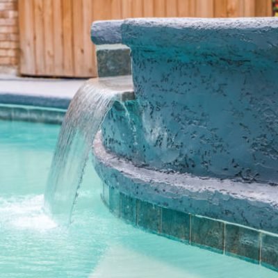 A Hot Tub hot tub next to a large freeform swimming pool with a waterfall water feature running.