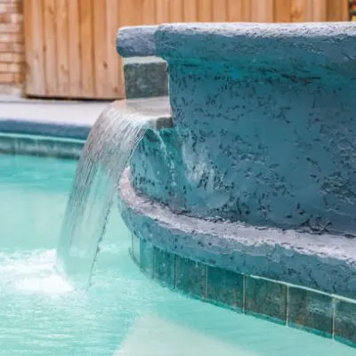 A Hot Tub hot tub next to a large freeform swimming pool with a waterfall water feature running.